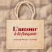 Sac jute "L'amour à la française" avec personnalisation "Juliette & Thomas - mai2022", écriture rouge présenté sur sable